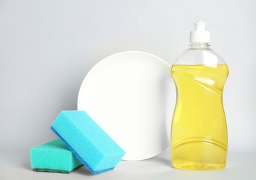 Photo of Detergent, plate and sponges on light background. Clean dishes
