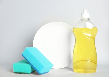 Detergent, plate and sponges on light background. Clean dishes