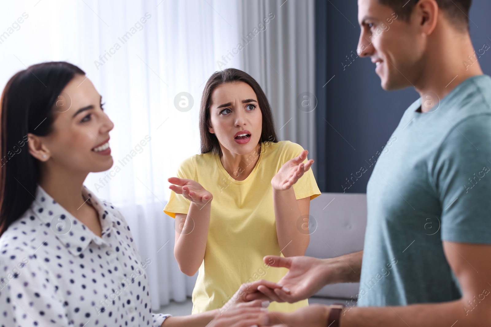 Photo of Unhappy woman feeling jealous while couple spending time together at home