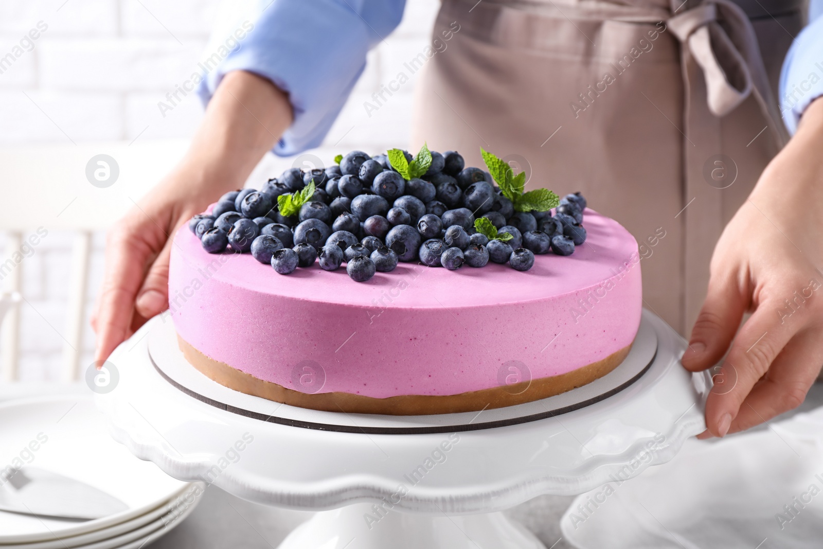 Photo of Young woman with tasty blueberry cake at table, closeup