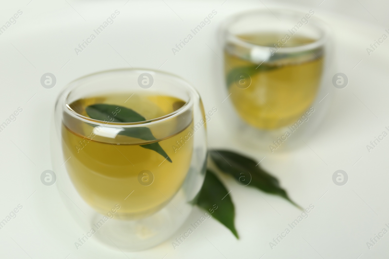 Photo of Aromatic green tea and leaves on white table