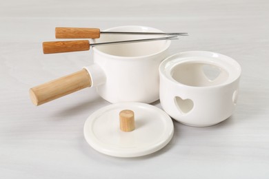 Photo of Fondue set on white wooden table. Kitchen equipment