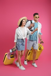 Photo of Couple of tourists with tickets, passports and suitcases on pink background