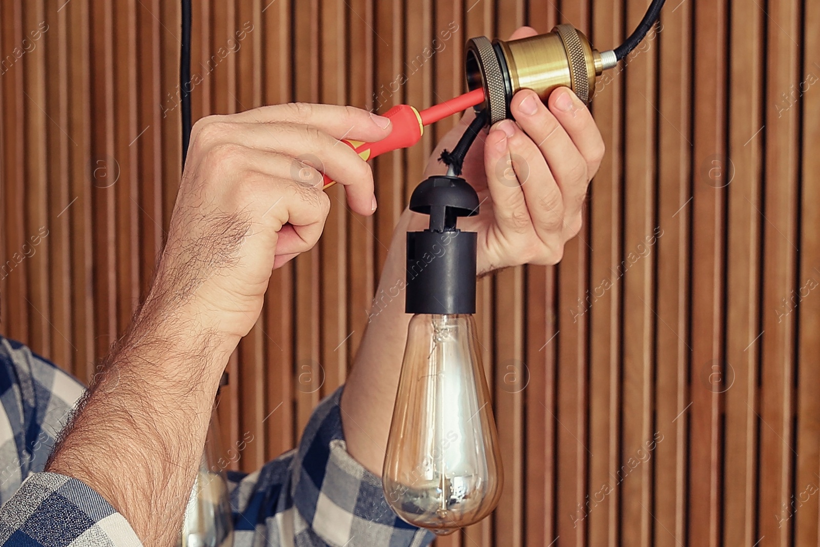 Image of Electrician with screwdriver repairing ceiling lamp indoors, closeup