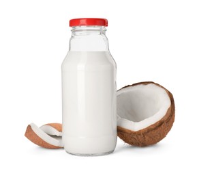 Glass bottle of delicious vegan milk and coconut pieces on white background