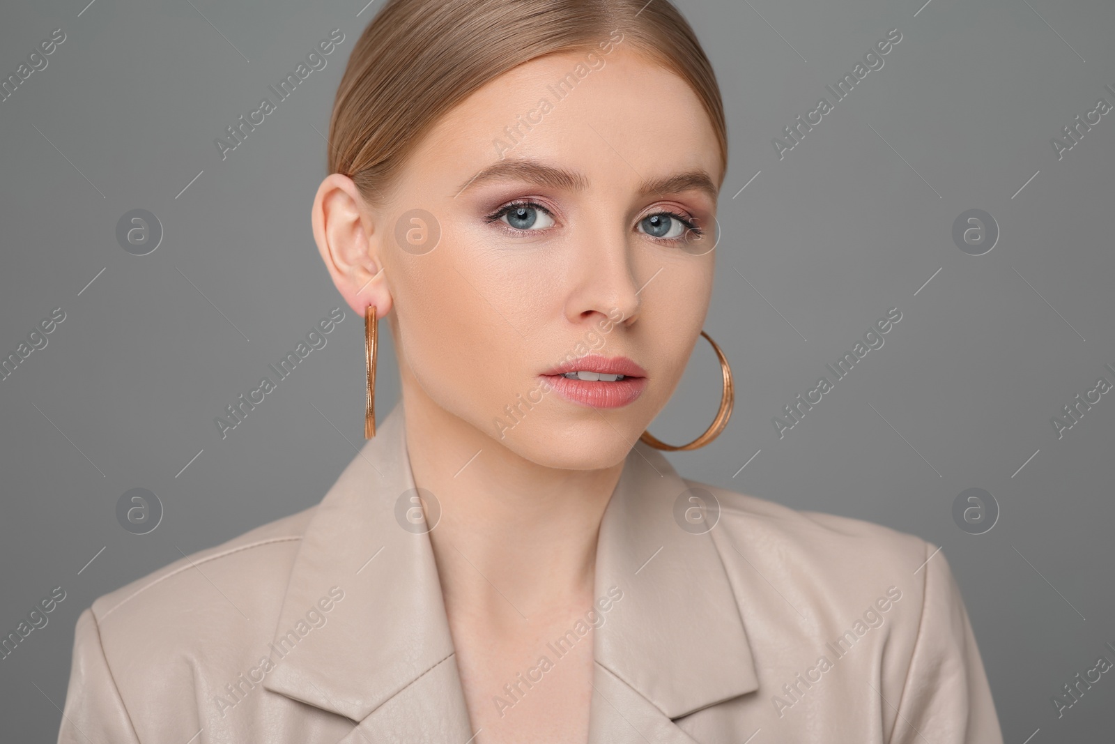 Photo of Beautiful young woman with elegant earrings on gray background