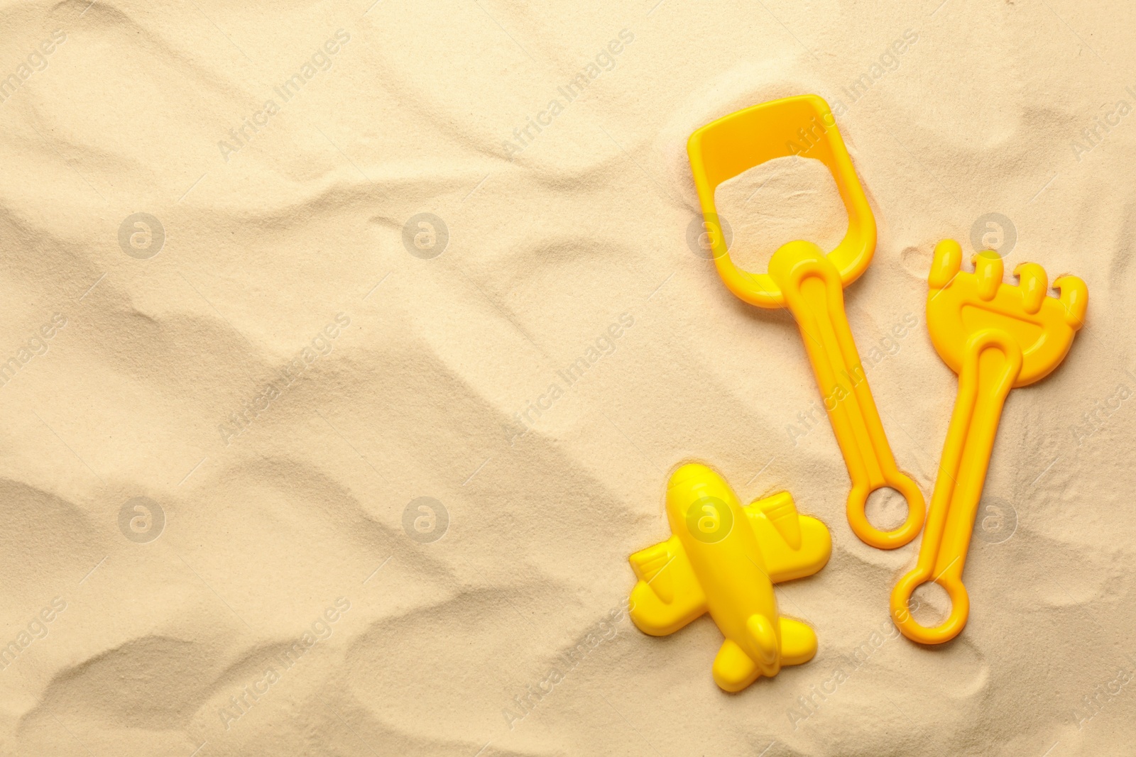 Photo of Flat lay of beach toy kit on sand, space for text. Outdoor play