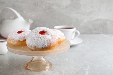 Photo of Pastry stand with delicious jelly donuts on grey table. Space for text
