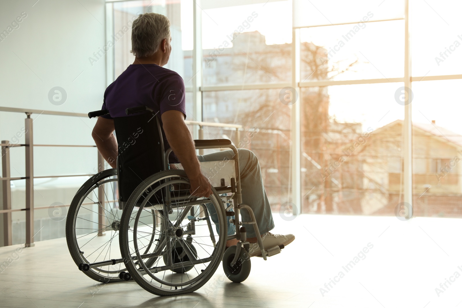 Photo of Senior man sitting in wheelchair near window at home