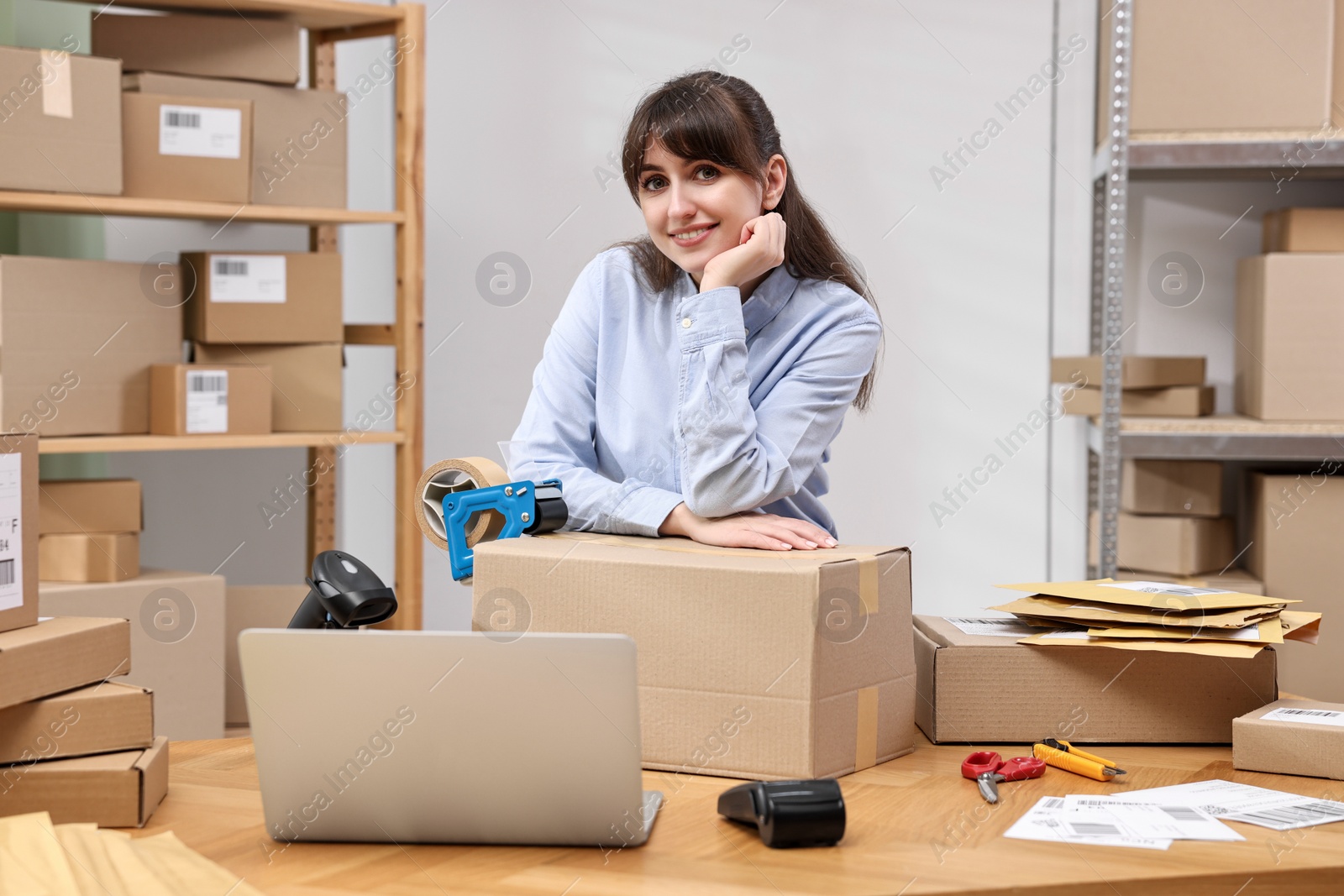 Photo of Parcel packing. Post office worker with box at wooden table indoors