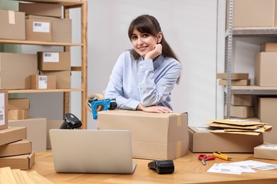 Photo of Parcel packing. Post office worker with box at wooden table indoors