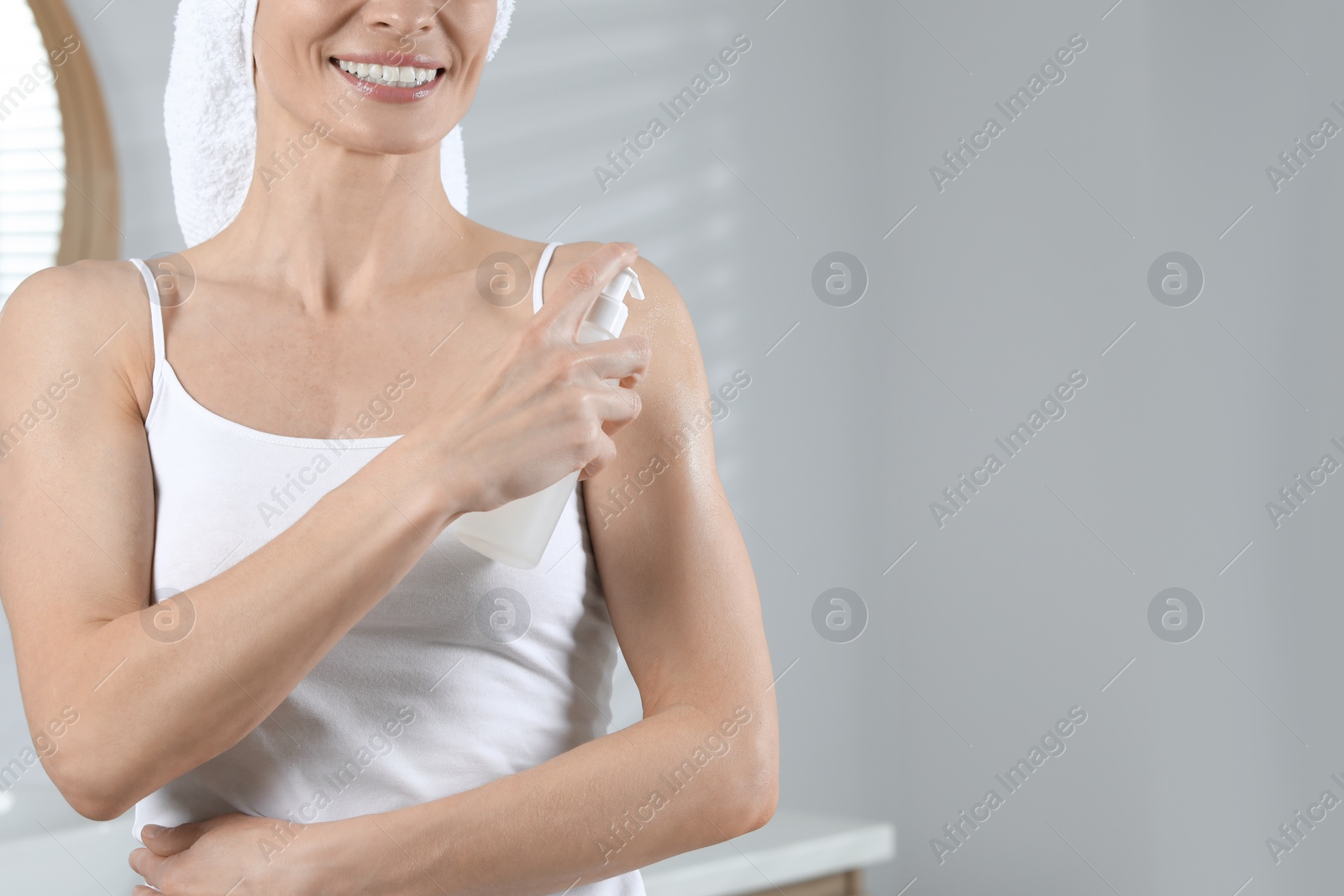 Photo of Woman applying body oil onto shoulder in bathroom, closeup. Space for text