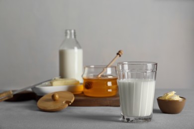 Glass with milk, honey and butter on grey table