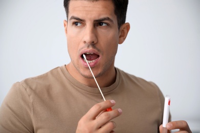 Man taking sample for DNA test on light background