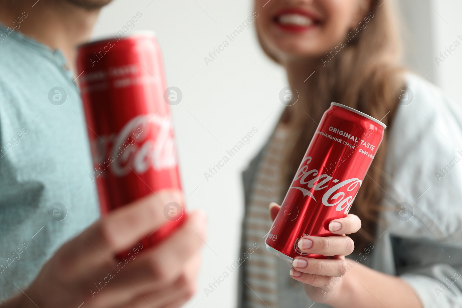 Photo of MYKOLAIV, UKRAINE - NOVEMBER 28, 2018: Young couple with Coca-Cola cans indoors, closeup