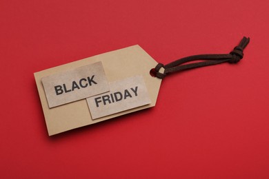 Photo of Tag with words Black Friday on red background, top view