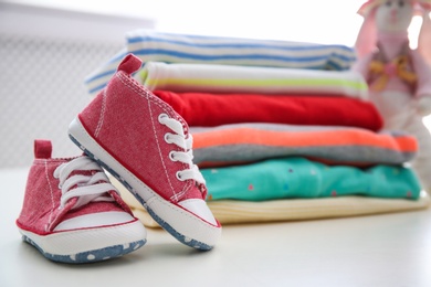 Child shoes and stack of clothes on background