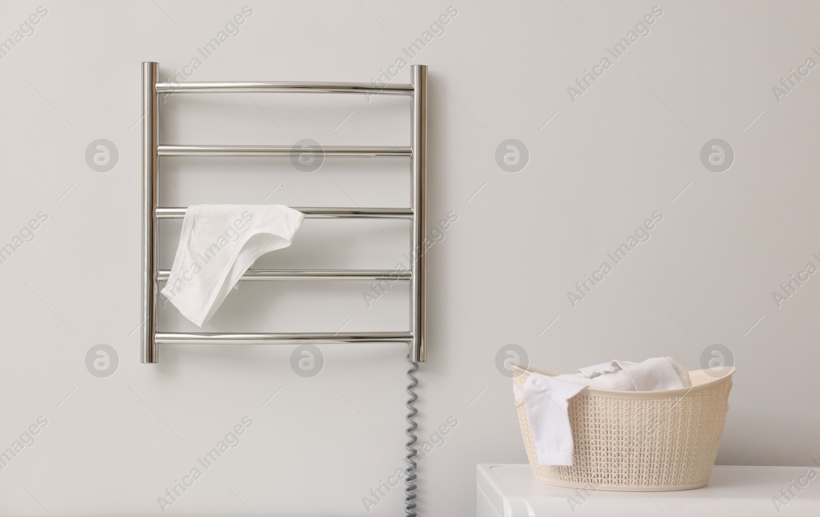 Photo of Heated towel rail with underwear on white wall in bathroom