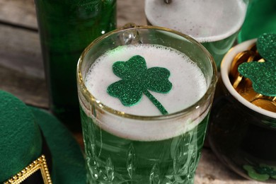 Photo of St. Patrick's day party. Green beer, leprechaun hat, pot of gold and decorative clover leaves on wooden table, closeup
