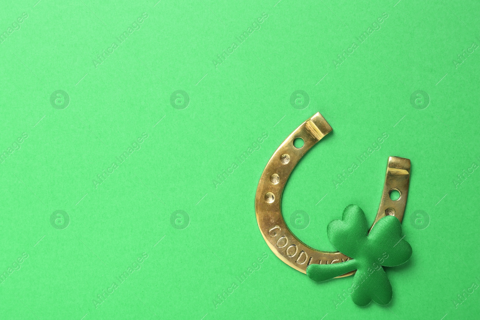 Photo of Decorative clover leaf and horseshoe on green background, flat lay with space for text. St. Patrick's Day celebration