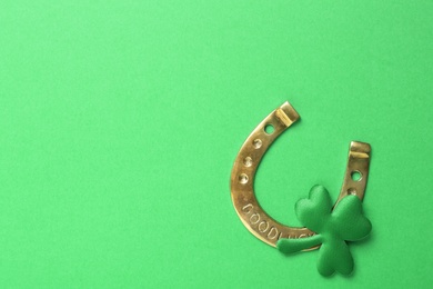 Decorative clover leaf and horseshoe on green background, flat lay with space for text. St. Patrick's Day celebration