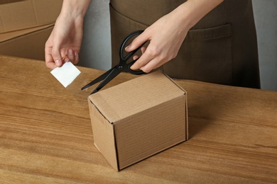 Photo of Woman packing box at table, closeup. Space for design