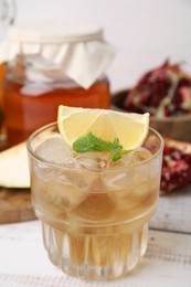 Tasty kombucha and ice cubes in glass on white wooden table, closeup