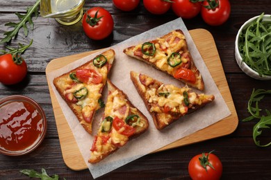 Photo of Tasty pizza toasts and ingredients on wooden table, flat lay