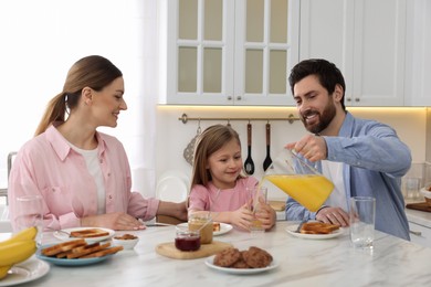 Happy family having breakfast at table in kitchen