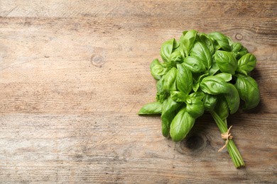 Photo of Fresh basil on wooden table, top view. Space for text