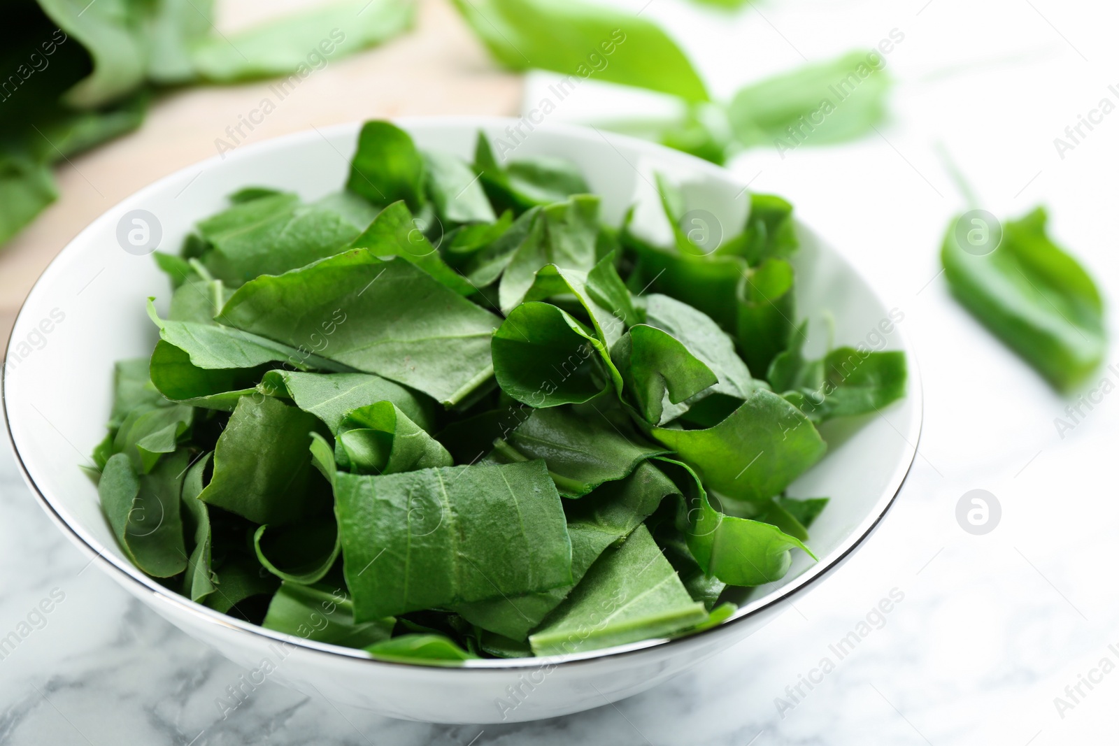 Photo of Fresh green sorrel leaves on white marble table, closeup