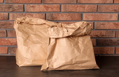 Photo of Paper bags on table against brick wall. Mockup for design