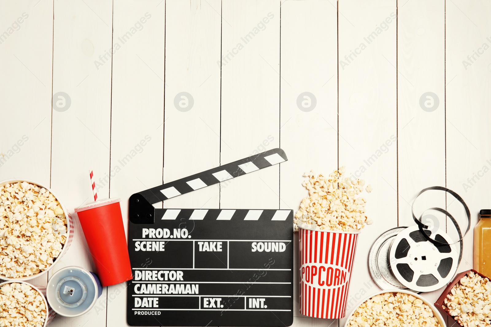 Photo of Flat lay composition with popcorn, cinema clapperboard and space for text on white wooden background