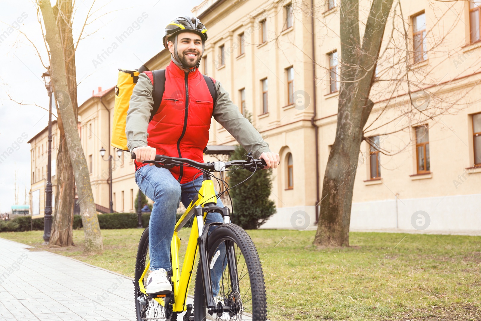 Photo of Courier with thermo bag riding bicycle outdoors. Food delivery service