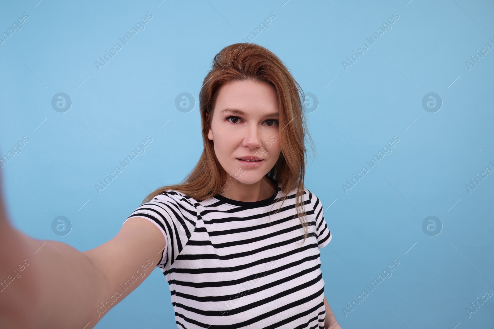 Photo of Beautiful woman taking selfie on light blue background