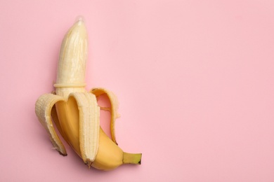 Photo of Banana with condom and space for text on pink background, top view. Safe sex