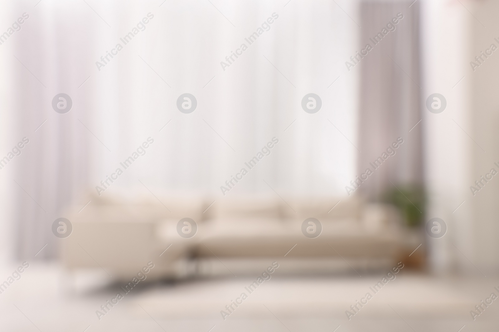 Photo of Blurred view of comfortable sofa and window with beautiful curtains in room. Interior design