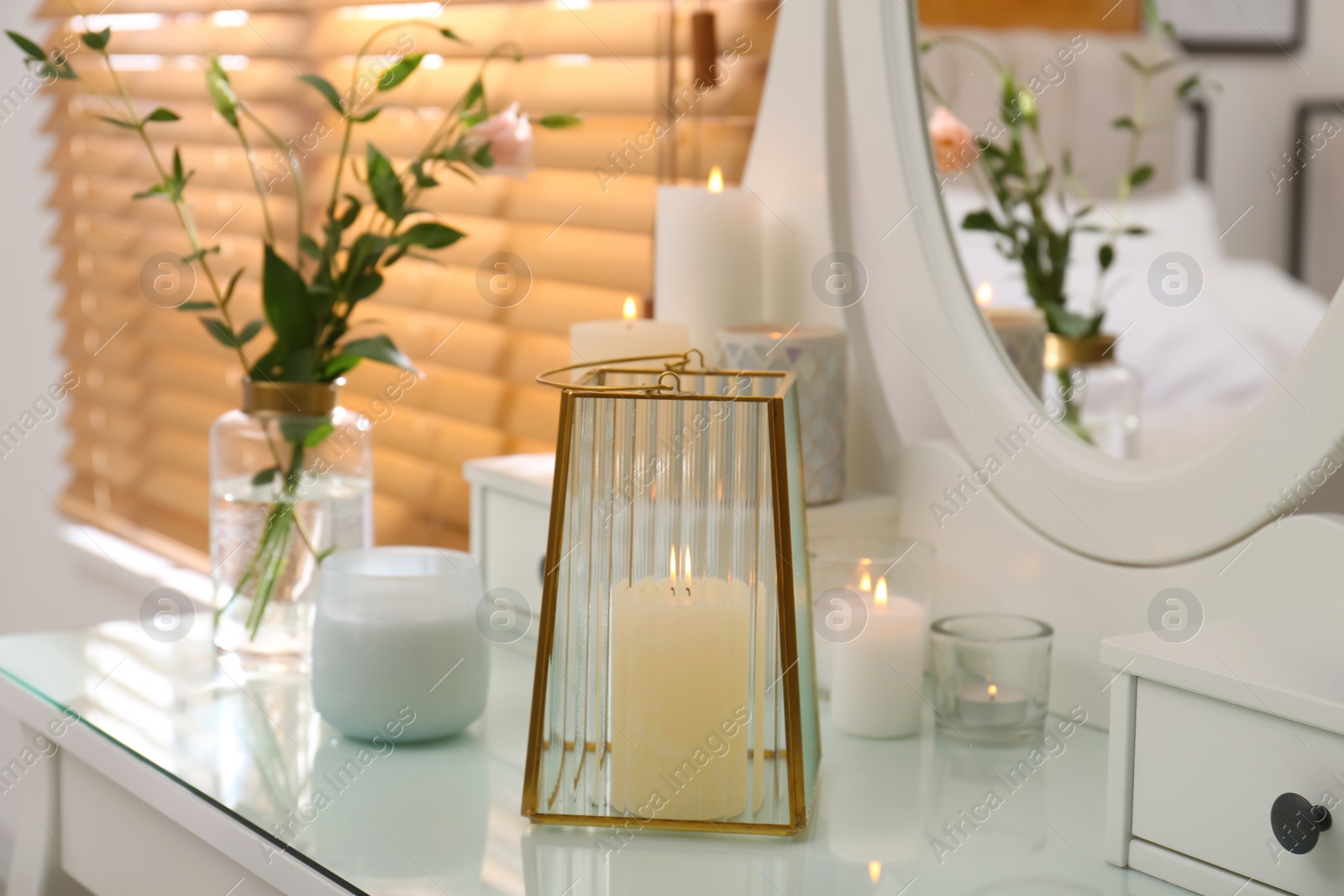 Photo of Burning scented candles and bouquet on dressing table indoors