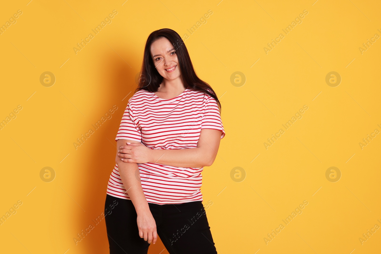 Photo of Beautiful overweight woman with charming smile on yellow background. Space for text