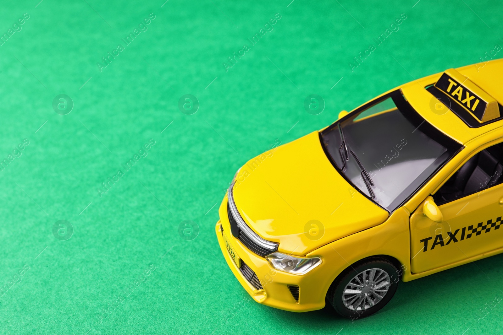 Photo of Yellow taxi car model on green background. Space for text