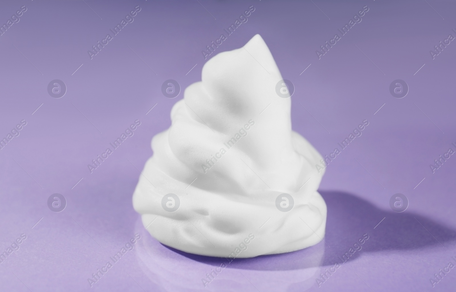 Photo of Sample of cleansing foam on violet background, closeup. Cosmetic product