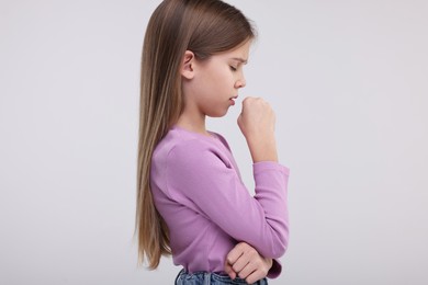 Photo of Sick girl coughing on light background. Cold symptoms