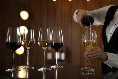 Waitress pouring wine into glass in restaurant, closeup