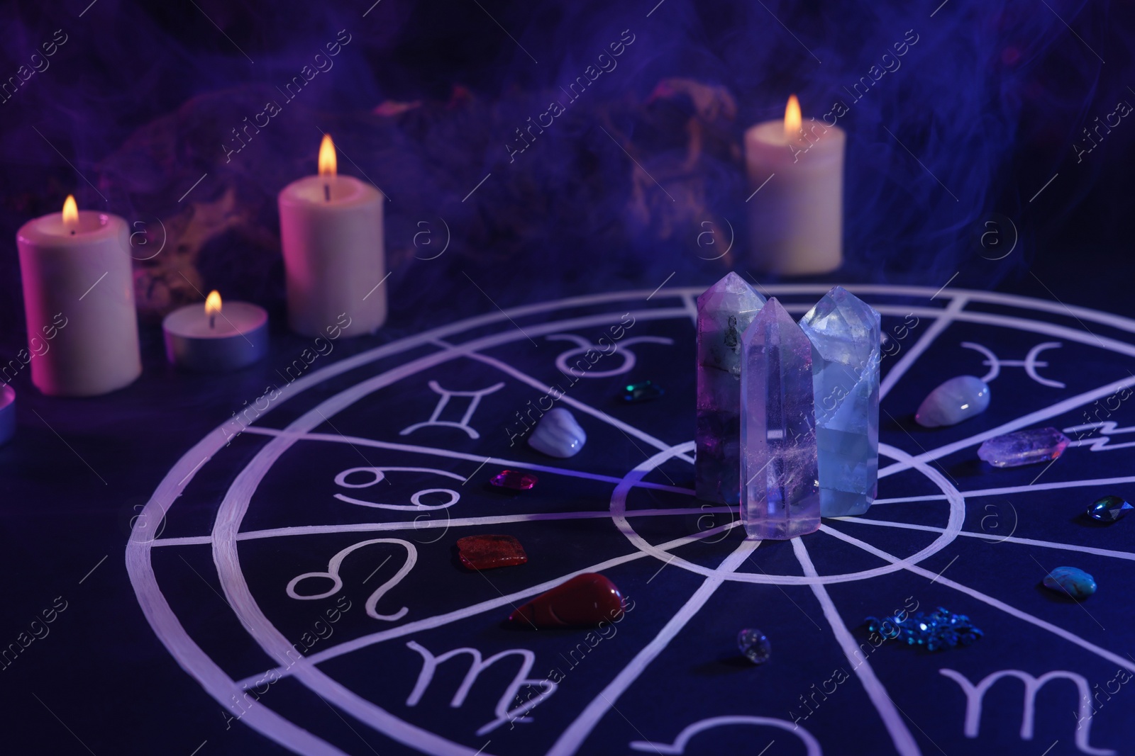 Photo of Natural stones for zodiac signs, drawn astrology chart and burning candles on black table. Color tone effect