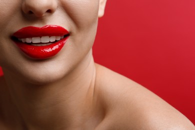 Photo of Closeup view of woman with beautiful lips on red background. Space for text