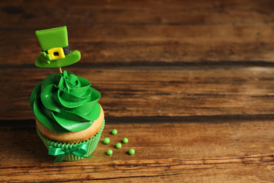 Delicious decorated cupcake on wooden table, space for text. St. Patrick's Day celebration