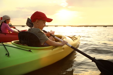 Photo of Happy children kayaking on river at sunset. Summer camp activity