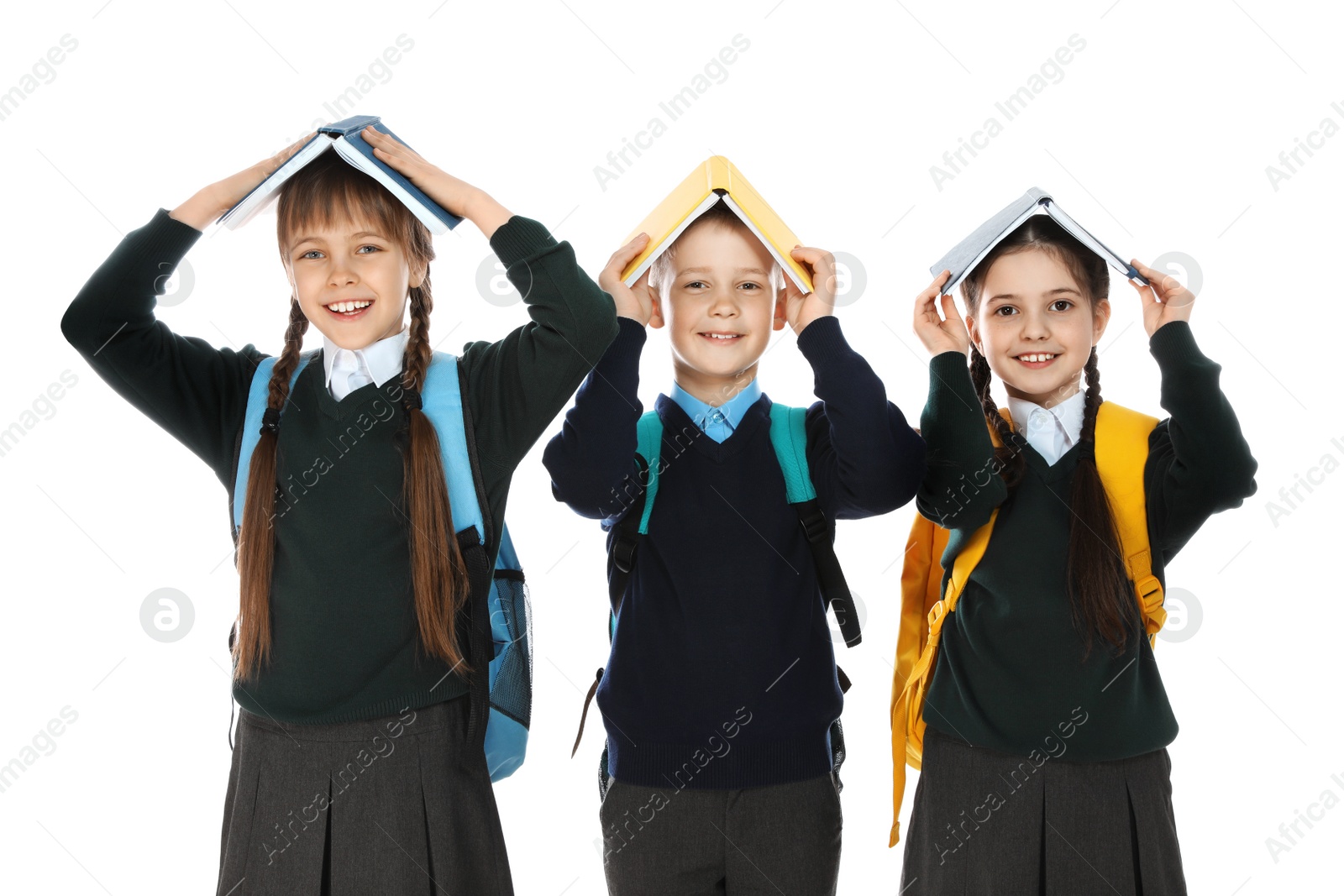 Photo of Portrait of funny children in school uniform with books on heads against white background