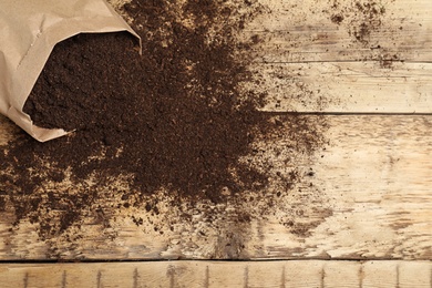 Photo of Paper bag and soil on wooden table, top view with space for text. Gardening season