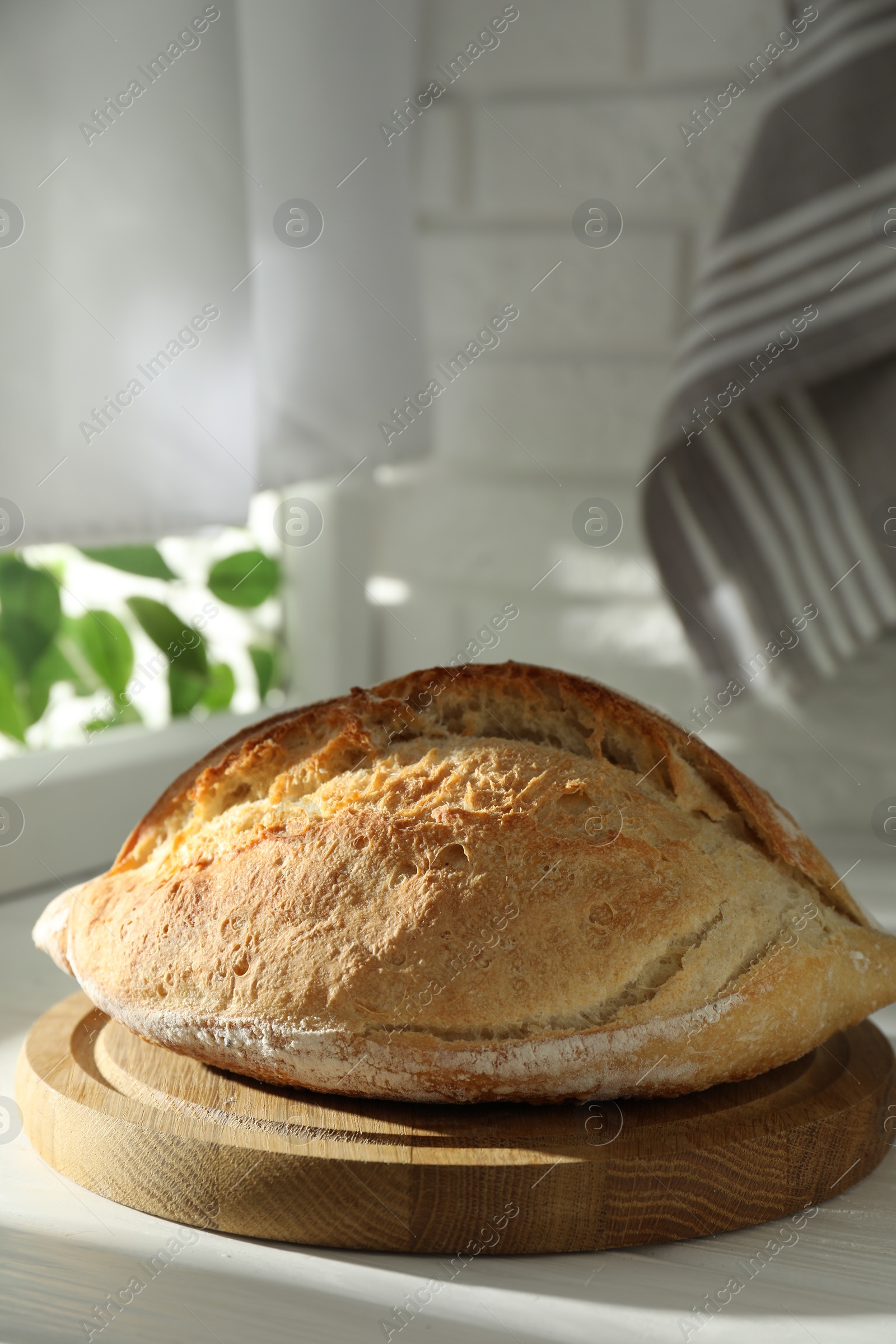 Photo of Freshly baked sourdough bread on white wooden table indoors